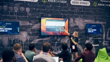 Infosecurity Europe attendees watch a cybersecurity conference session at the Geek Street stage
