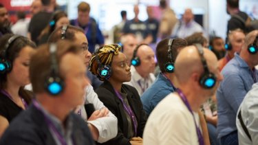  Cybersecurity professionals with electronic headsets watching an information security conference session 