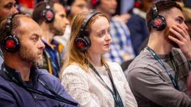 Attendees wearing headphones while listening to a speaker