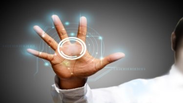 A man wearing a white shirt holds up his hand, engaging with an advanced touch screen technology.