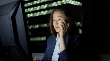 A woman dressed in a business suit, actively talking on the phone